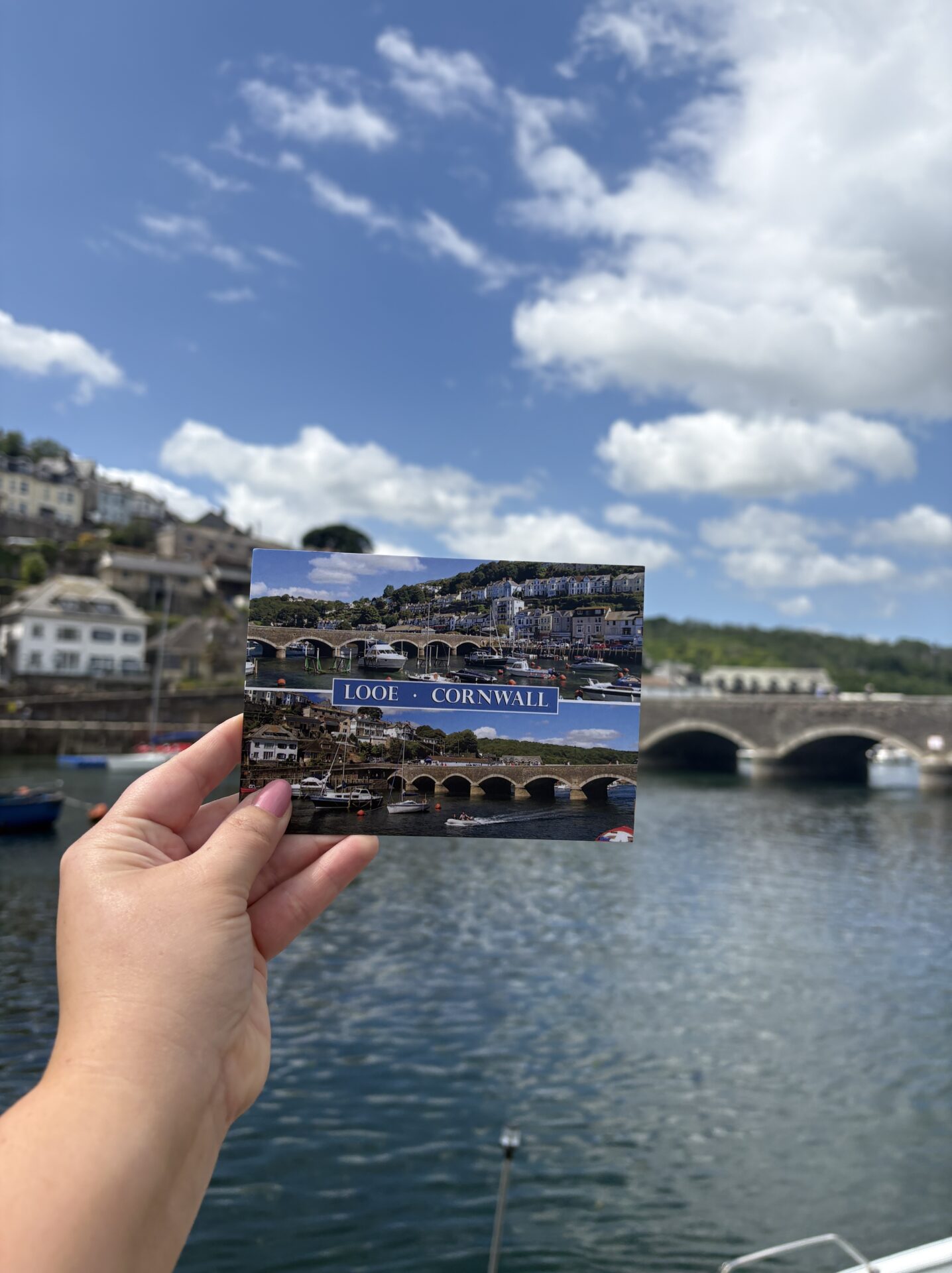 Hand holding a postcard of Looe, Cornwall